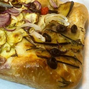 Close de uma Focaccia Vegetariana de Fermentação natural Longa da padaria artesanal delivery Conexão Delícia seguro por uma mão