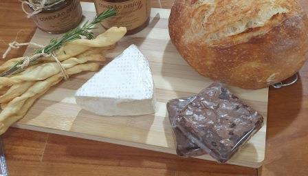 Pão Italiano, Grissini, Brownie e Queijo Brie sobre uma tábua de pães