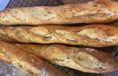 Baguete Italiana Crosta Parmesão 4 Baguete Italiana Crosta Parmesão sobre uma mesa de madeira e grade de aço da Padaria Artesanal Delivery Conexão Delícia