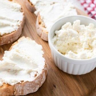 Pasta de Ricota e ervas em um pote e sobre três fatias de pães